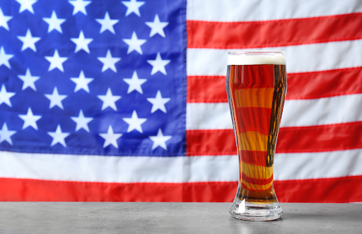 glass of beer in front of an American flag, showing that this is American made beer.
