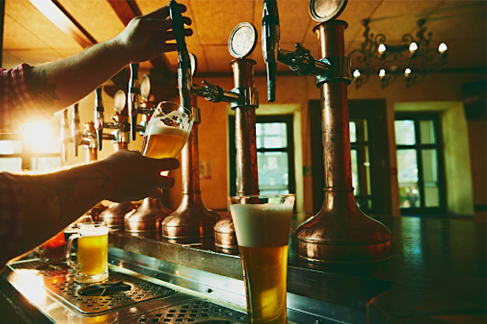 A bartender pouring beer from some draft beer towers.