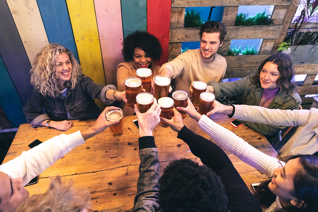 A group of beer lovers having fun and celebrating with pints of draft beer.